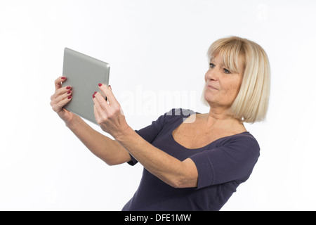Senior woman using a tablet computer photographed in studio on white background Stock Photo