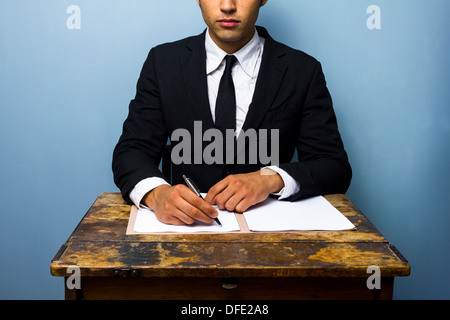 Young businessman is sitting at an old desk and signing a contract Stock Photo