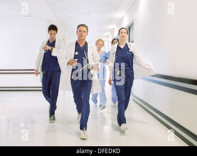 Doctors rushing down hospital corridor Stock Photo