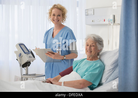 Portrait of smiling nurse and senior patient in hospital room Stock Photo