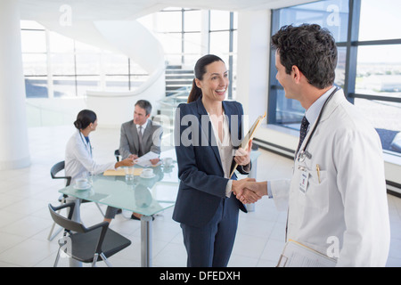 Doctor and businesswoman handshaking in meeting Stock Photo