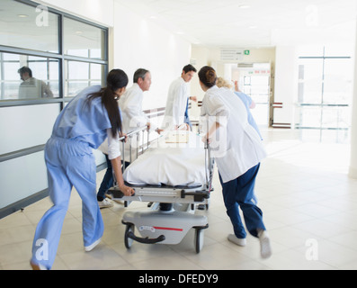 Doctors rushing patient on stretcher down hospital corridor Stock Photo
