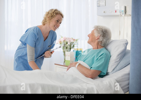 Nurse and aging patient talking in hospital room Stock Photo