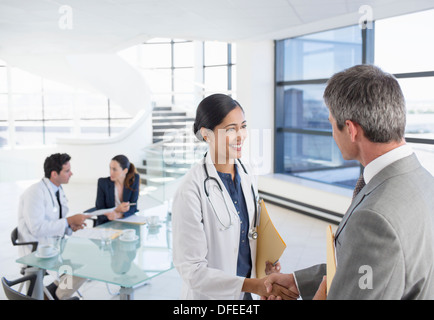 Doctor and businessman handshaking in meeting Stock Photo