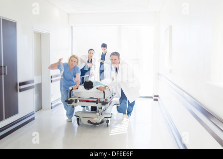 Doctors and nurses rushing patient on stretcher down hospital corridor Stock Photo