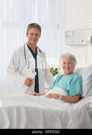 Portrait of smiling doctor and senior patient in hospital room Stock Photo