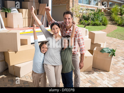 Portrait of family cheering near moving van in driveway Stock Photo