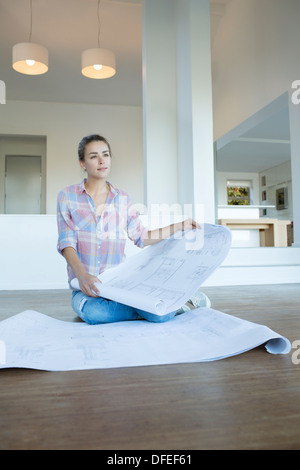 Woman with blueprints on floor in new house Stock Photo