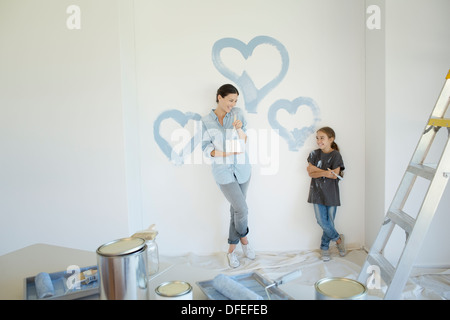 Mother and daughter painting blue hearts on wall Stock Photo