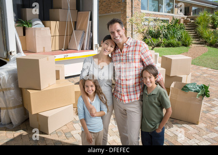Portrait of smiling family standing near moving van in driveway Stock Photo