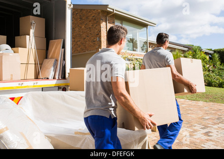 Movers carrying boxes in new house Stock Photo