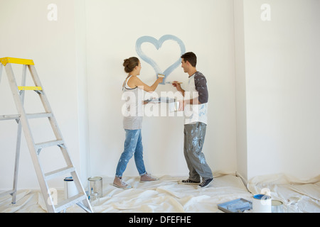 Couple painting blue heart on wall Stock Photo