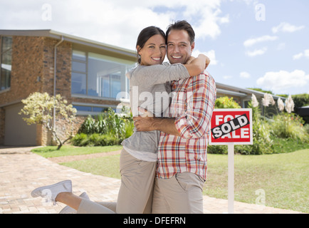 Portrait of smiling couple hugging outside new house Stock Photo