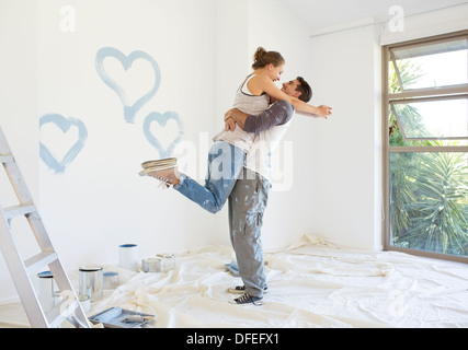 Couple painting blue hearts on wall Stock Photo