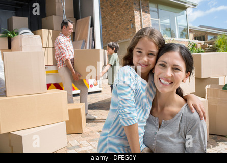 Mother and daughter smiling by moving van in driveway Stock Photo