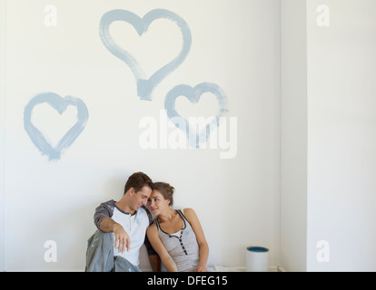 Couple painting blue hearts on wall Stock Photo