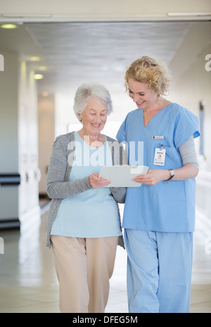 Nurse and aging patient reading chart in hospital corridor Stock Photo