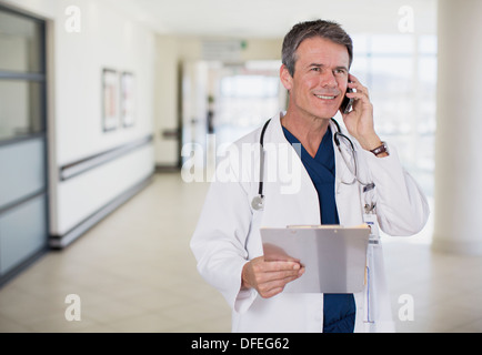 Doctor talking on cell phone in hospital corridor Stock Photo