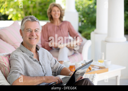 Senior man using laptop on patio Stock Photo