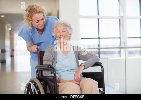 Nurse and aging patient smiling in hospital corridor Stock Photo