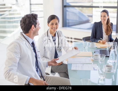 Doctors and businesswoman talking in meeting Stock Photo