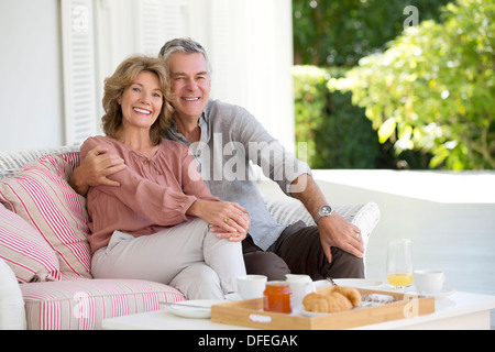 Portrait of smiling senior couple enjoying breakfast on patio Stock Photo