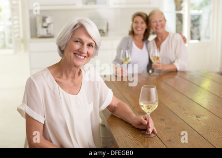 Senior women drinking white wine in kitchen Stock Photo