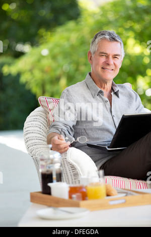 Senior man using laptop on patio Stock Photo