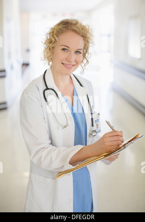 Doctor writing on clipboard in hospital corridor Stock Photo
