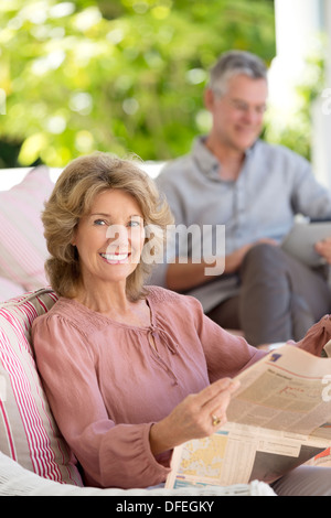 Portrait of senior woman reading newspaper on patio Stock Photo