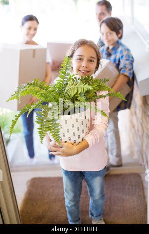 Portrait of smiling family moving belongings into house Stock Photo