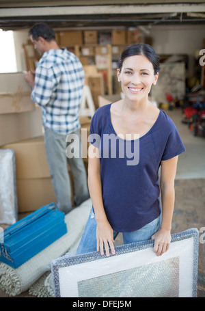 Woman holding picture in driveway among cardboard boxes Stock Photo