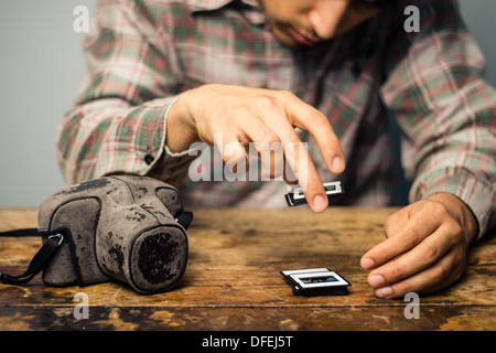 Young photographer is sitting at a table and looking over his old slides Stock Photo