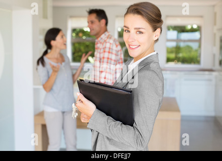 Portrait of smiling realtor with couple in background Stock Photo