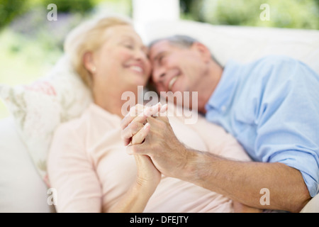 Senior couple holding hands on sofa