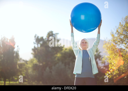 Senior woman holding fitness ball in park Stock Photo