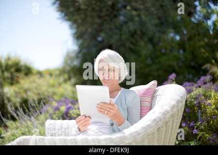 Senior woman using digital tablet in armchair Stock Photo