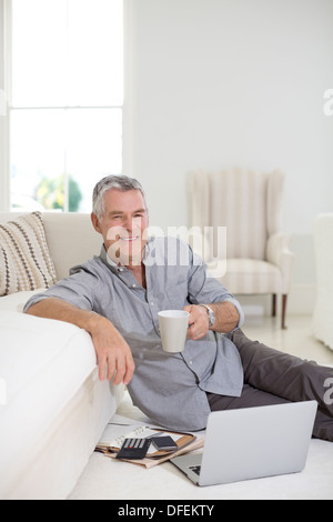 Senior man using laptop on living room floor Stock Photo