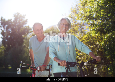 Senior couple walking bicycles in park Stock Photo