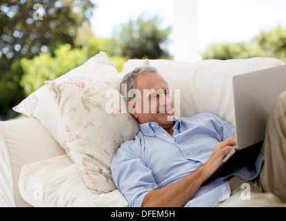 Senior man using laptop on patio sofa Stock Photo