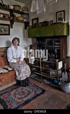 Woman employee of The Black Country Living Museum welcoming visitors in a preserved 1800's/early 1900's cottage type home. Victorian era room England Stock Photo