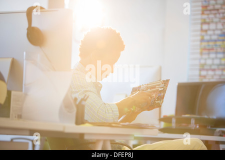 Businessman holding circuit board in sunny office Stock Photo