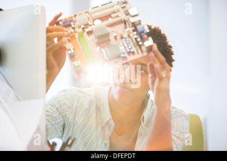 Businessman examining circuit board in office Stock Photo
