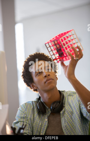 Businessman examining cube in office Stock Photo