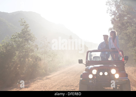 Friends driving sport utility vehicle on dirt road Stock Photo
