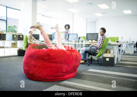 Businesswoman playing in beanbag chair in office Stock Photo