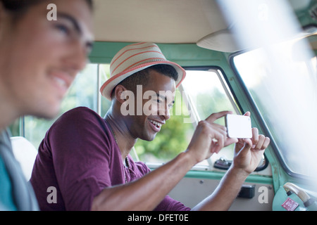 Man using camera phone in camper van Stock Photo