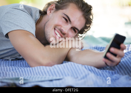 Man using cell phone on picnic blanket Stock Photo