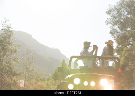 Man taking pictures of girlfriend in sport utility vehicle Stock Photo