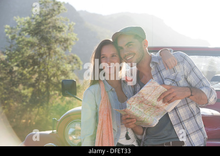 Smiling couple with map next to sport utility vehicle Stock Photo